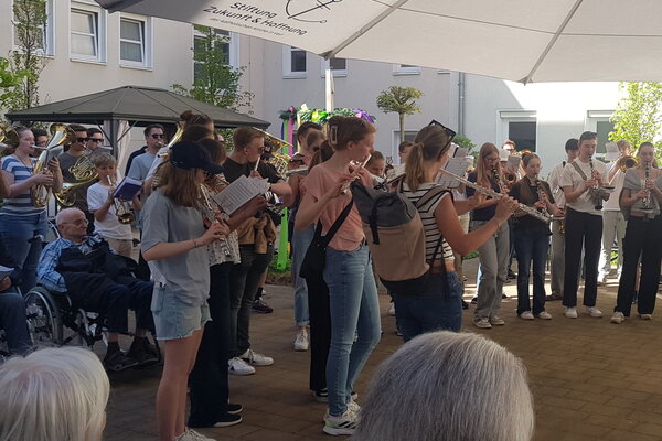 Junge Musiker:innen spielen ein Konzert unter einem großen Sonnenschirm.